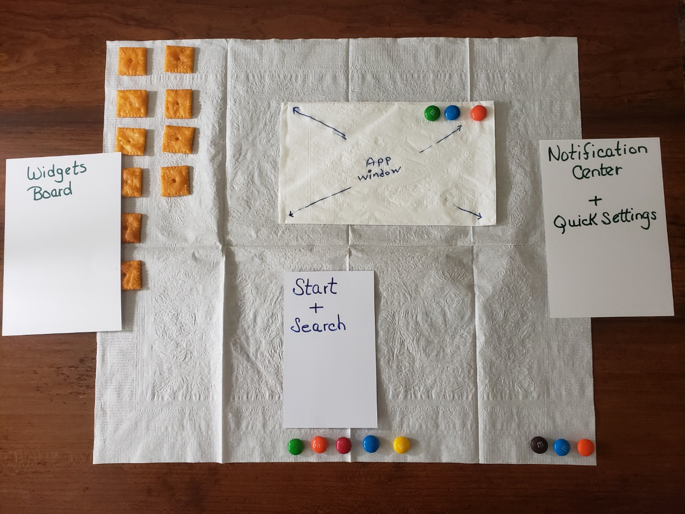 Windows 11 Orientation Snack Game showing an open napkin with snack crackers, candies, and index cards representing various parts of the Windows 11 desktop.